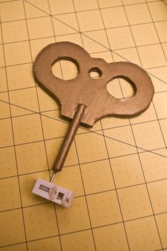 an old key is laying on the floor with a tape measure in front of it