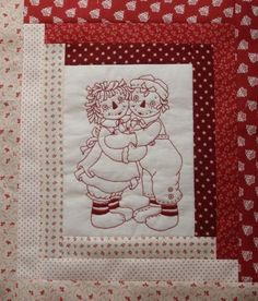 two children hugging each other on a red and white patchwork quilted wall hanging