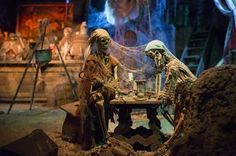 two skeletons are sitting at a table in front of a stage set with lights on