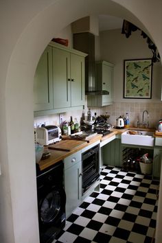 a kitchen with black and white checkered flooring next to an archway in the wall