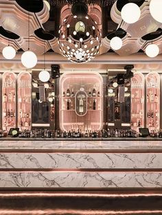 an elegant bar with marble counter tops and lights hanging from the ceiling, along with chandeliers