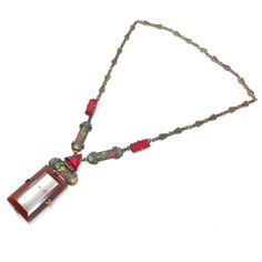 This beautiful necklace, reflects the craftsmanship and eye for detail characteristic of Czechoslovakian jewellery design.  Condition Report: Excellent The Details... This gilded metal necklace features pressed metal bow designs along its length. At the centre of the necklace, there are emerald and triangular cut, claw set, red glass panels. There are also gilded metal panels detailed with geometric designs that are accented with red, blue and green enamel. Suspended from the centre of the neckl Bow Designs, Czech Jewelry, Metal Bow, Pressed Metal, Vintage Pendant Necklace, Bold Floral Print, 1920s Art, Metal Necklace, 1920s Art Deco