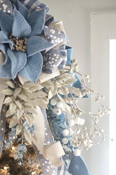 a christmas tree decorated with blue and white ribbons, bows and flowers on top of it