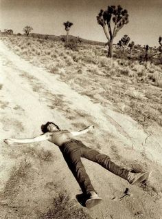 a man laying on the side of a dirt road