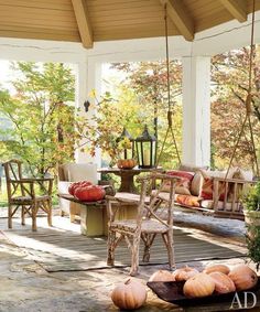 a porch with chairs and pumpkins on the ground