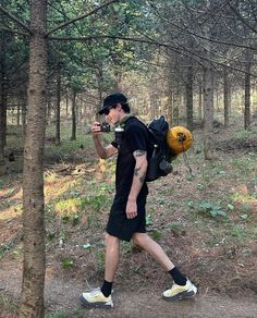 a man walking through the woods with a backpack on his back and a camera in his hand