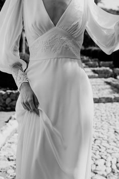 a woman in a long white dress standing on rocks