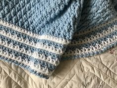 two blue and white crocheted blankets laying on top of each other