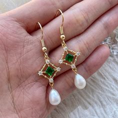 Handmade 14K REAL gold-filled green emerald/crystal lace dangle earrings, with genuine natural ivory pearls. Stunning emerald gemstone gives elegant, classy and dainty sparkles. Absolutely modern elegant minimalism. Each earring is crafted with care using high-quality materials, including genuine emeralds, natural pearls, and 14K gold-filled lace. The intricate lace design adds a touch of old-world glamour to these earrings, making them perfect for any special occasion. Whether you're looking to Green And Gold Wedding Jewelry, Gold Jewelry With Green Dress, Wedding Earrings Emerald, Green And Gold Outfit Classy, Green And Pearl Earrings, Emerald Dangle Earrings, Emerald And Gold Earrings, Emerald Wedding Earrings, Pearl And Emerald Earrings