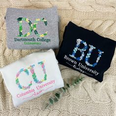 three embroidered t - shirts are laying on a blanket with flowers and leaves around them