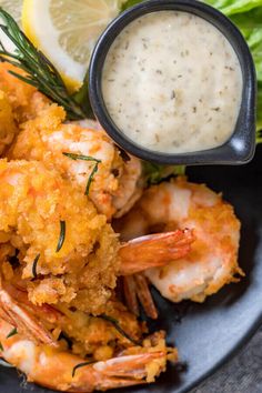 a plate full of shrimp with sauce and lemon wedges next to some lettuce