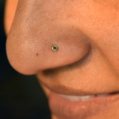 a woman's nose with a tiny green jewel in the middle of her nose