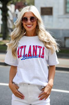 Calling all Braves fans, the Heather Grey Atlanta Baseball Tee was made just for you! This comfy tee is designed with a soft and stretchy knit. It features a crew neckline, short sleeves, a relaxed fit, and the words "Atlanta Baseball" on the front. Style the Heather Grey Atlanta Baseball Tee with your favorite distressed denim and a baseball hat for the perfect game day look! Champion Brand Soft + Stretchy Knit Fabrication "Atlanta Baseball" Graphic Crew Neckline Short Sleeves Relaxed Fit 100% Casual T-shirt For Game Day In Spring, Trendy Game Day Short Sleeve T-shirt, Trendy Short Sleeve T-shirt For Game Day, Summer Game Day T-shirt With Text Print, Stretch Crew Neck T-shirt With Text Print, Spring Varsity T-shirt With Graphic Print, Sporty T-shirt For Spring Fan Merchandise, Spring Cotton Varsity T-shirt, Spring Short Sleeve T-shirt With Lettering