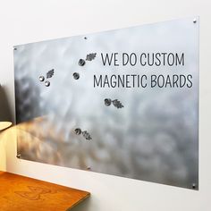 a sign that says we do custom magnetic boards on the wall next to a lamp