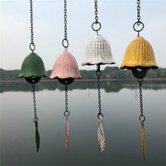 four different colored lamps hanging from chains over water