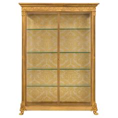 an antique display case with glass shelves and gold trimmings on the front, against a white background