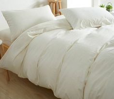 an unmade bed with white sheets and pillows