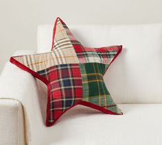 a red and green plaid star pillow on a white couch