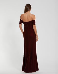 the back of a woman in a long velvet dress, looking down at her shoulder