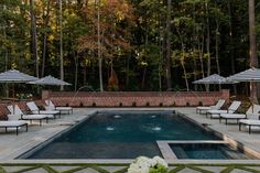 an outdoor pool surrounded by lawn chairs and umbrellas