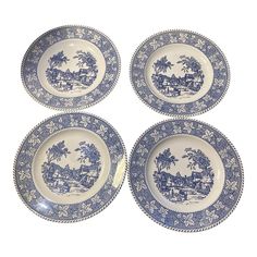 four blue and white plates with images of animals in the woods on them, set against a white background