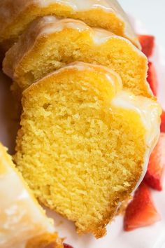 a white plate topped with slices of cake and covered in icing next to strawberries