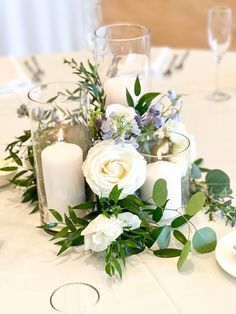 a table with candles, flowers and greenery is set up for a wedding reception