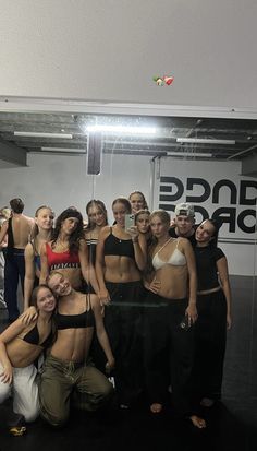 a group of people posing for a photo in front of a dance studio sign and mirror