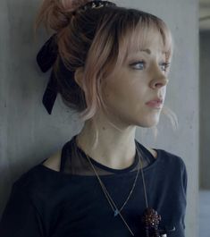 a woman wearing a black shirt with a bow in her hair looking off to the side