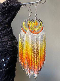 a woman wearing a black dress and earrings with beads hanging from it's sides