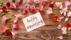 a piece of paper with the words happy anniversary on it surrounded by pink and red flowers