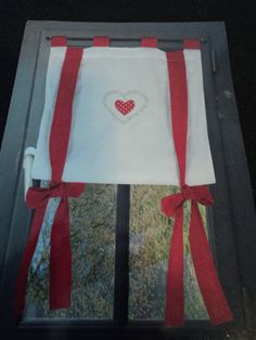 the window is decorated with red ribbon and a heart embroidered on it's side