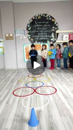 a group of children standing in front of a chalkboard with circles on it and a blue cone