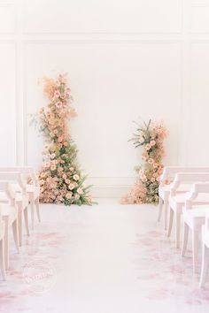 two rows of white chairs sitting next to each other in front of a flower covered wall