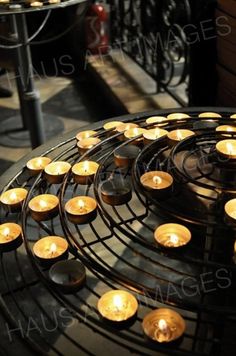 many lit candles sitting on top of a metal rack