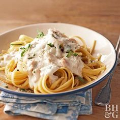 a white bowl filled with pasta covered in sauce and parmesan on top of a wooden table