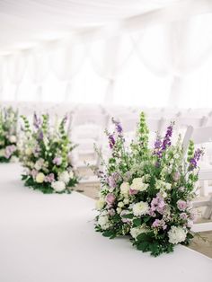 the flowers are sitting on the tables at the wedding ceremony in front of the white tent