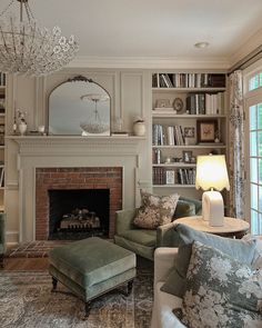 a living room filled with furniture and a fire place under a chandelier in front of a window