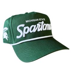 An angled view of a green baseball cap with Michigan State embroidered in white above an embroidered stylized script reading “Spartans” in white with a silver outline. Embroidered on the right temple panel is a white Spartan helmet. Over the bill is a white braided cord. Cheap Green Hats With Letter Print, Cheap Green Hats With Embroidered Logo, Collegiate Adjustable Trucker Hat With Curved Brim, Adjustable Collegiate Trucker Hat With Curved Bill, Collegiate Adjustable Snapback Trucker Hat, Adjustable Collegiate Trucker Hat Baseball Cap, Collegiate Style Adjustable Trucker Baseball Cap, Collegiate Style Adjustable Trucker Cap, Adjustable Curved Visor Trucker Hat For College