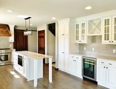 an empty kitchen with white cabinets and wood floors