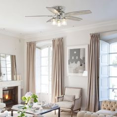 a living room filled with furniture and a fire place in front of a window covered in curtains