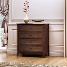 a vase with flowers on top of a wooden dresser