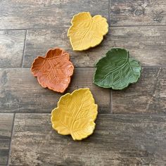 three leaf shaped dishes sitting on top of a wooden floor