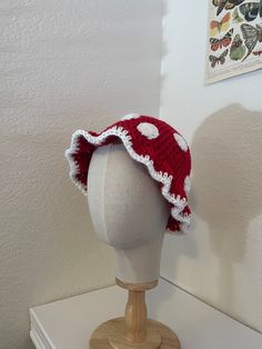 a red and white crocheted hat sitting on top of a mannequin head