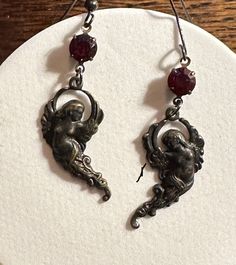 Black Brass Gothic Angel Dangle Earrings Finely detailed Stamped blackened brass Angel charms. 6mm faceted Swarovski crystals in ruby red set in antiqued brass. Approximately 60mm in length  Black Ear wire  This Listing is for one pair of earrings Thank you for stopping by Gothic Dangle Pierced Earrings, Adjustable Gothic Drop Earrings, Gothic Dangle Hoop Earrings, Gothic Silver Dangle Earrings, Black Victorian Dangle Earrings, Angel Charms, Spike Ring, Creepypasta Oc, Gothic Angel