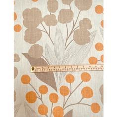 an orange and white flower print fabric with a measuring tape on it's side