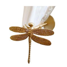 a golden dragonfly sitting on top of a white curtain