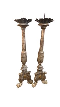 two metal candlesticks sitting next to each other