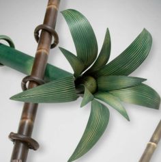 two bamboo sticks with green leaves on them next to some metal pens and an umbrella