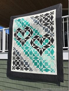 a quilt hanging on the side of a house with a window in the back ground